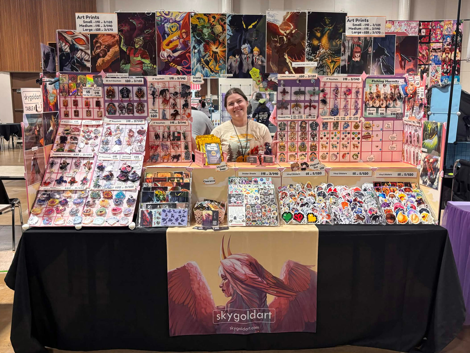 Table with various items and posters at a convention booth.